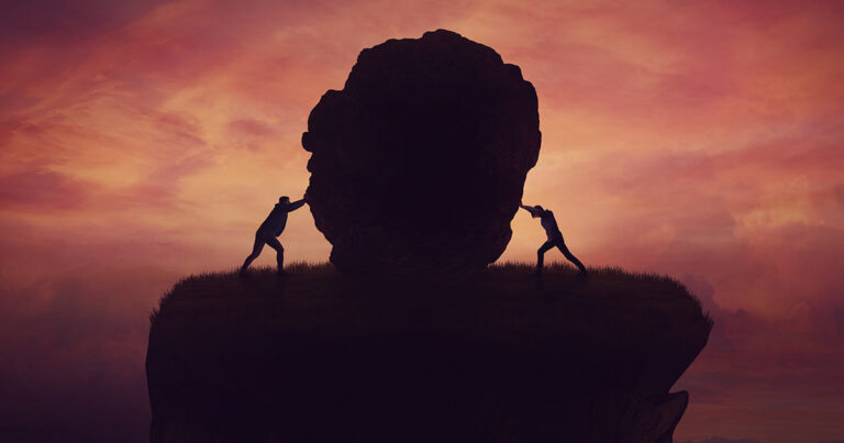 Two people struggling to push a rock together